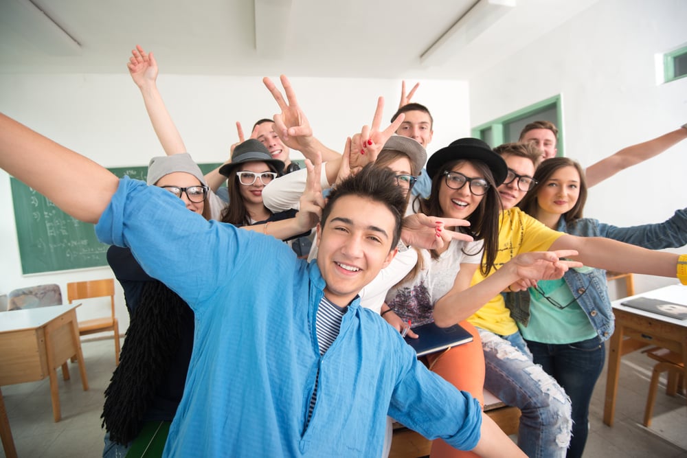 Cheerful classmates posing in classroom in front of a green board Cheerful classmates posing in classroom in front of a green board
